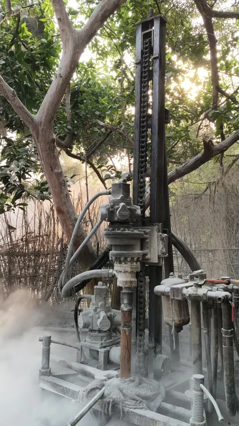 A portable borewell drilling machine operates outdoors amidst trees. Stock Footage 335773885