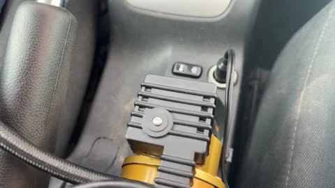 Portable electric air compressor operates inside a car while connected by hose, Vídeo Stock 337115147
