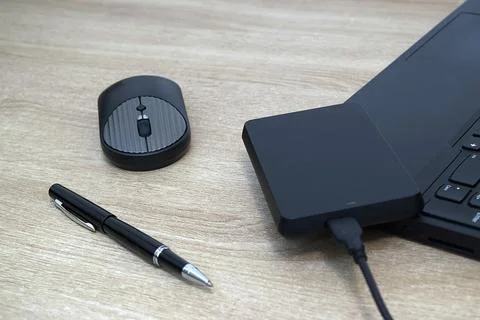 Portable External Hard Drive, Wireless Mouse, and Pen on Office Desk Stock Photos