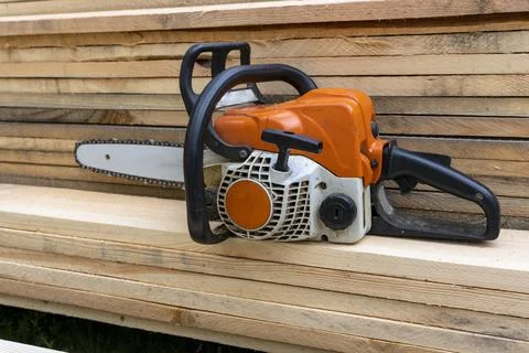 Portable gasoline chain saw on a stack of wooden planks. Stock Photos