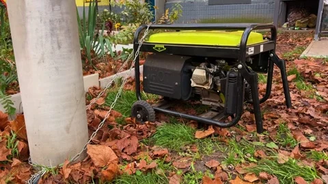 Portable generator secured with heavy chain to pillar running outdoors Stock Footage 321803360