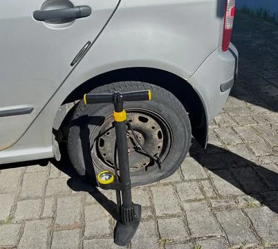 Portable hand pump ready to inflate a flat car tire. Stock Photos