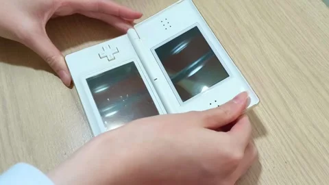 Portable handheld game console with stylus resting on a light wood table top, Video stock 318310927