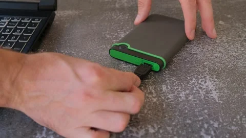 Portable hard drive connected to laptop to transfer data or documents, close-up Stock Footage 249740880