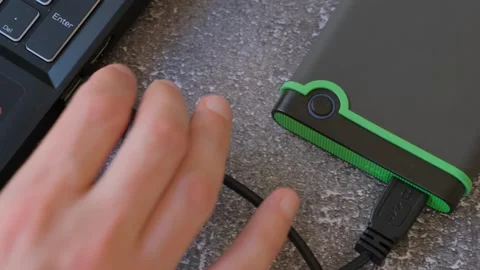 Portable hard drive connected to laptop to transfer data or documents, close-up Stock Footage 259208379