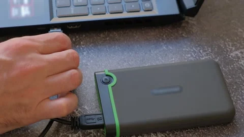 Portable hard drive connected to laptop to transfer data or documents, close-up Stock Footage 273379545