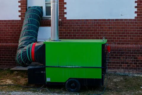 Portable heating unit connected to ventilation duct outdoors Stock Photos
