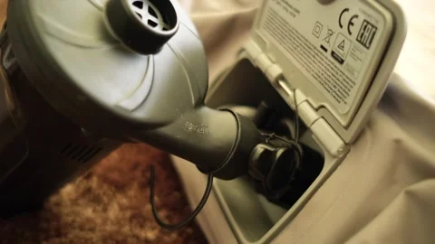 A portable mattress inflation pump inserted into the valve of a camping mattress Stock Footage 247077881