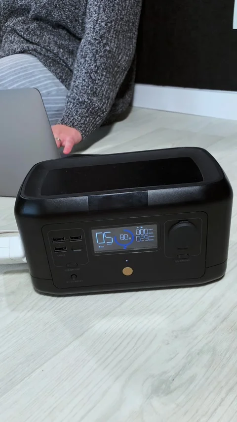 Portable power station charging devices on a wooden floor with a person in the Stock Footage 338430861
