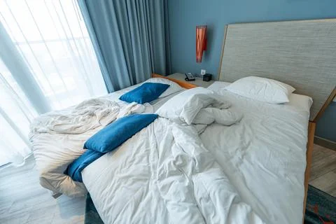 Portable rollaway extra bed with untidy linens prepared for housekeeping af.. Stock Photos