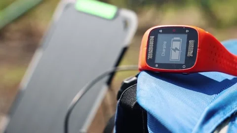 Portable solar panel charges a smartwatch on a blue backpack. Stock-Footage 157456213
