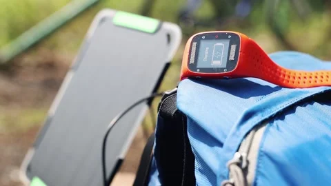 Portable solar panel charges a smartwatch on a blue backpack. Stock-Footage 157456216