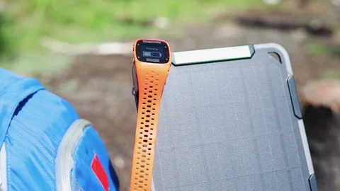 Portable solar panel charges a smartwatch on a blue backpack. Vídeo Stock 157456243