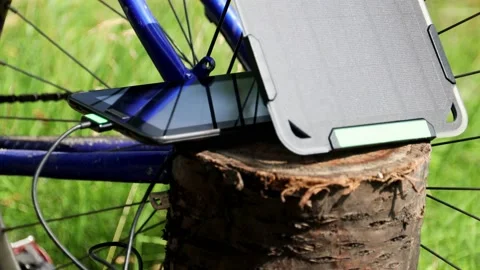 Portable solar panel charges a tablet on a tree stump in a summer day. Stock-Footage 157493987