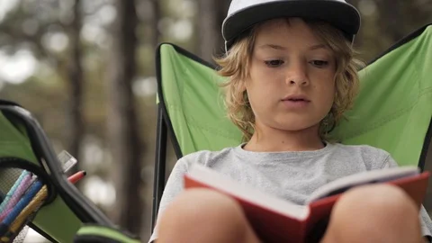 Portarit of child reading a book on pine wood background. Stock Footage 112013071