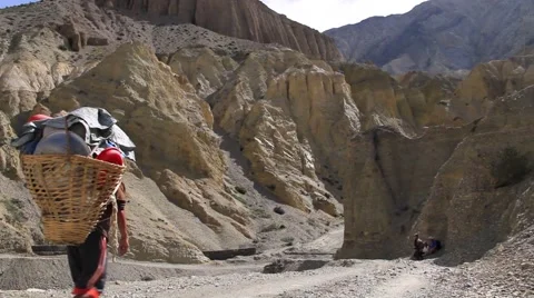 Porter walking through mountainous region carrying doko basket Stock Footage 62923885