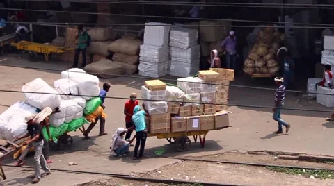 Porters with huge loads pull them across train tracks Stock Footage 58487121