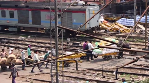 Porters with huge loads pull them across train tracks Stock Footage 58487357
