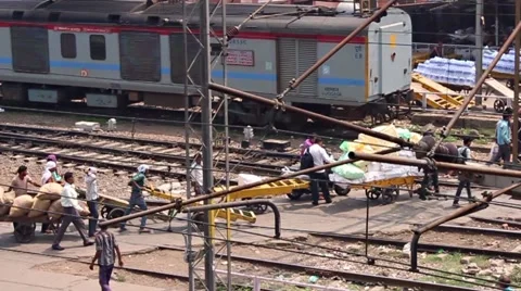 Porters with huge loads pull them across train tracks Stock Footage 58492210