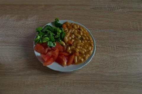 Portion of cooked ripe white beans and fresh tomato and cucumber salad Stock Photos
