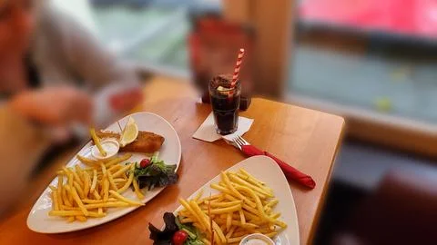 Portion of crispy breaded fish fillet with French fries served on a plate Stock Photos