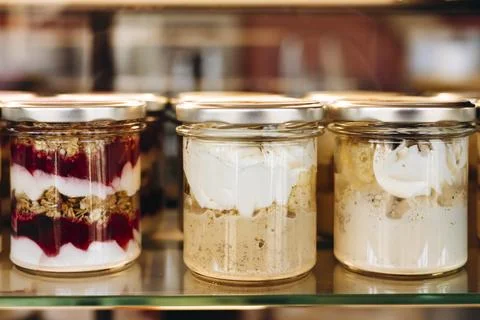 Portion desserts served in jars displayed on a pastry shop or cafe showcase. Stock Photos
