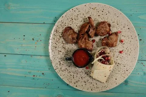Portion of grilled meat with side and sauce on round plate, angled view on .. Foto stock