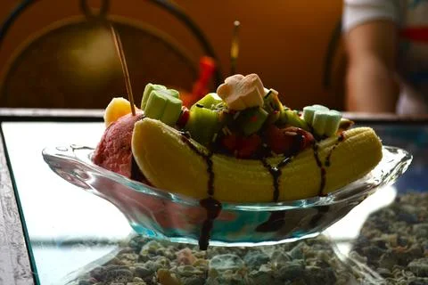 A portion of iced banana split is served on a clear table Stock Photos