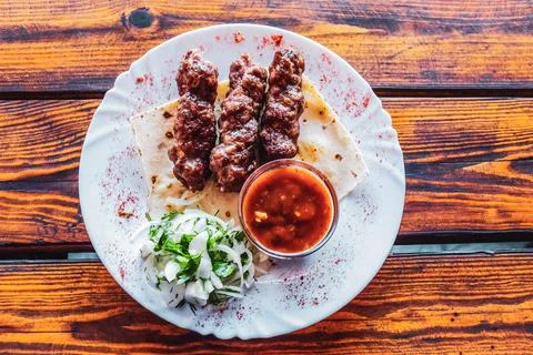 Portion luleh kebab on a plate. Appetizing dish on the wooden table. Stock Photos