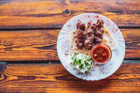 Portion luleh kebab on a plate. Appetizing dish on the wooden table. Stock Photos