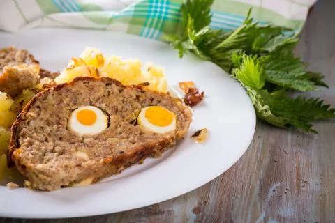 Portion of meatloaf on white plate with mashed potatoes and fresh nettle Stock Photos