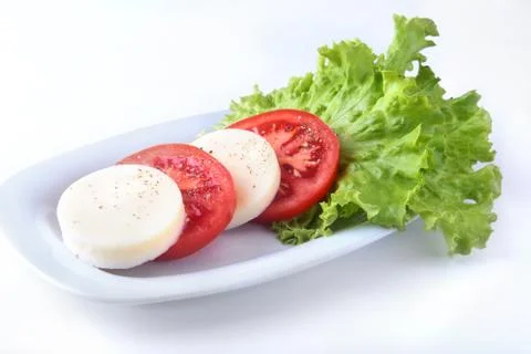 Portion of Mozzarella with Tomatoes, lettuce leaf and Balsamic dressing on white Stock Photos