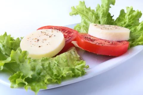 Portion of Mozzarella with Tomatoes, lettuce leaf and Balsamic dressing on white Stock Photos