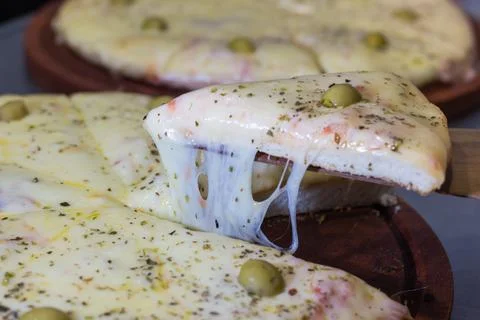 Portion of pizza with cheese in the foreground Stock Photos