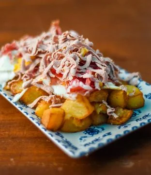 Portion of potatoes with fried eggs and cured Iberian ham. Stock Photos