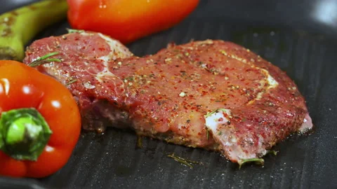 Portion of raw meat on a griddle with fresh vegetables Stock Footage 162860889