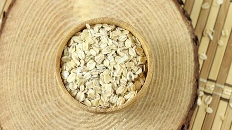 Portion of raw rolled oats rotating in wooden bowl Stock Footage 275511621