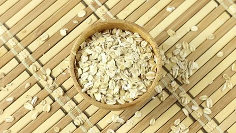 Portion of raw rolled oats rotating in wooden bowl Stock Footage 275511905