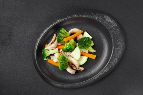 Portion of side dish in black plate - assorted steamed vegetables Stock Photos