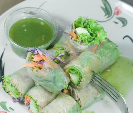 Portion of spring rolls on old wood with spicy sauce, vegetables and in noodl Stock Photos