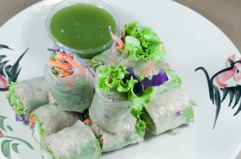 Portion of spring rolls on old wood with spicy sauce, vegetables and in noodl Stock Photos