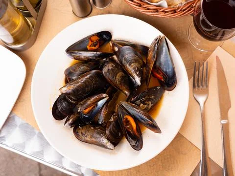 Portion of steamed mussels served with bay leaf on plate. Spanish dish mejillon Stock Photos