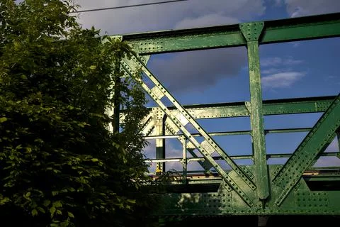 Portion of the structure of a railroad bridge framed by a tree Stock Photos