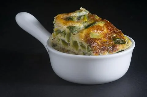 Portion of vegetable omelette in white ceramic bowl Stock Photos