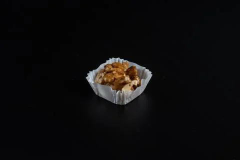 Portion of walnuts in a paper muffin cup on a black background Stock Photos