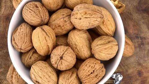 Portion of Walnuts rotating on a wooden plate (not loopale; 4K) Stock Footage