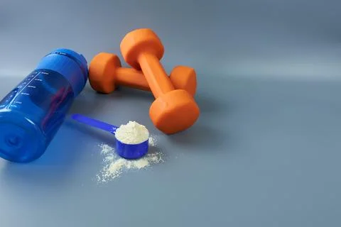 Portion of whey protein with shaker and dumbbells on gray background. Stock Photos