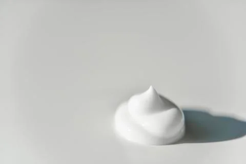 Portion of white cream on white background with the side light Foto stock