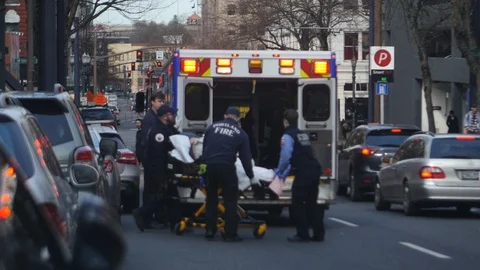 PORTLAND, OR Mar, 2019: EMTs load patient on stretcher into ambulance Stock Footage
