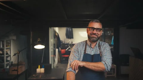 Portrait 30s European man looking at camera smiling, handsome man in workshop Stock Footage
